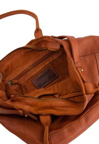 Sac à main en cuir véritable marron avec une surface texturée, doté d'une poche zippée, d'une doublure intérieure et d'une étiquette de marque. Le design comprend des poignées robustes.