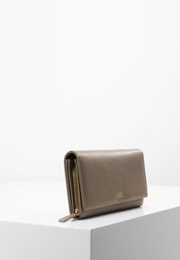 Gray faux leather wallet with a fold-over design, gold accents, and a zippered compartment. Smooth texture and minimal branding on the front.