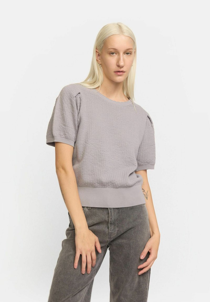 Pulover tricotat gri deschis, cu mâneci scurte tip puff, tiv cu dungi și model texturat. Asortat cu pantaloni largi gri închis.