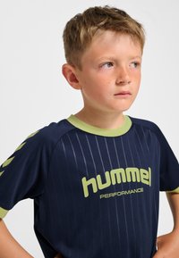 Marinblå sporttröja med vertikala ränder, ljusgröna detaljer på kragen och ärmarna samt "hummel PERFORMANCE"-logotyp i fet stil.