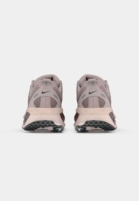 Buty biegowe Nike z miękką różową siateczką na cholewce, ciemnoczerwonymi akcentami, grubą beżową podeszwą środkową oraz teksturowaną czarną gumową podeszwą zewnętrzną.