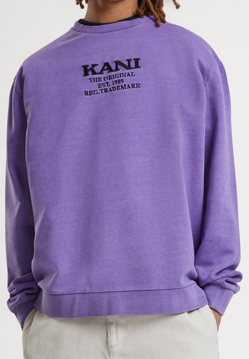 Sweatshirt in cotone viola con scollo rotondo, polsini a costine e logo sul petto anteriore con testo in ricamo nero.
