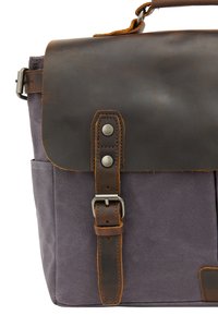 Canvas messenger taske i mørkegrå med en brun læderklap. Har en spænde rem og metal detaljer for sikker lukning.