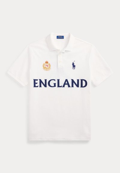 Λευκό πόλο μπλουζάκι με την επιγραφή "ENGLAND" σε σκούρα μπλε γράμματα, ένα κόκκινο και χρυσό έμβλημα στο αριστερό στήθος και το σκούρο μπλε λογότυπο Polo Ralph Lauren στο δεξί στήθος.