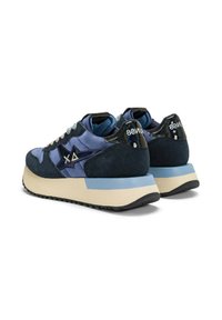 Sneaker in suede blu e blu navy con lacci bianchi, logo geometrico laterale, suole spesse color crema e blu, viste da dietro e di lato.