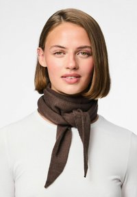 Écharpe en tricot marron stylisée avec un nœud, présentant une texture lisse et des extrémités pointues, portée sur une chemise claire.