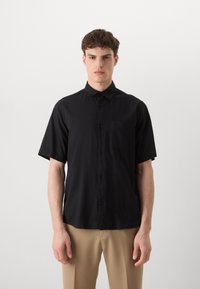 Camicia nera a maniche corte con bottoni in tessuto leggero, dotata di colletto e di una tasca sul petto; texture liscia e vestibilità comoda.