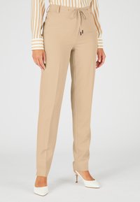 Beige op maat gemaakte broeken met een trekkoord in de taille, gemaakt van soepel stof. Heeft een rechte pijpdesign en is bedoeld om boven de enkel te zitten.