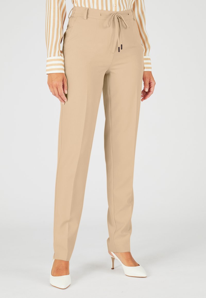 Beige op maat gemaakte broeken met een trekkoord in de taille, gemaakt van soepel stof. Heeft een rechte pijpdesign en is bedoeld om boven de enkel te zitten.