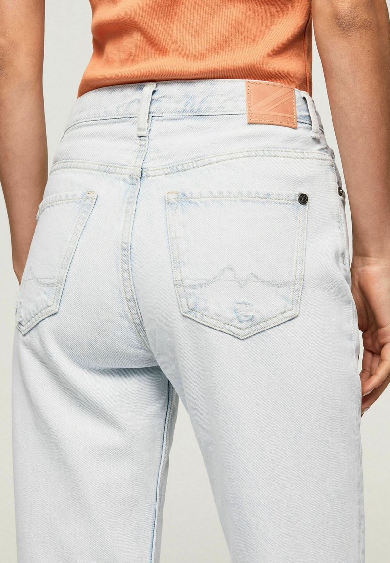 Hellblaue Jeans aus Denim mit hoher Taille, ausgestattet mit Gesäßtaschen, einem Lederpatch und subtilen Verblassungseffekten.