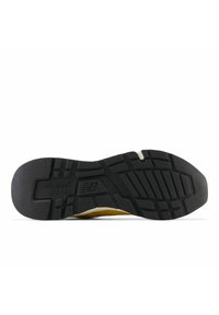 Svart gummisula med texturerat grepp, som har en upphöjd logotyp och olika mönster för dragkraft. Designen inkluderar en gul accent.