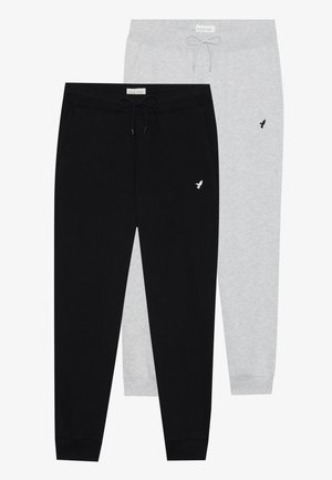 Twee paren joggingbroeken: één in het zwart en één in lichtgrijs. Beide hebben elastische taillebanden met drawstrings en een klein logo aan de zijkant.