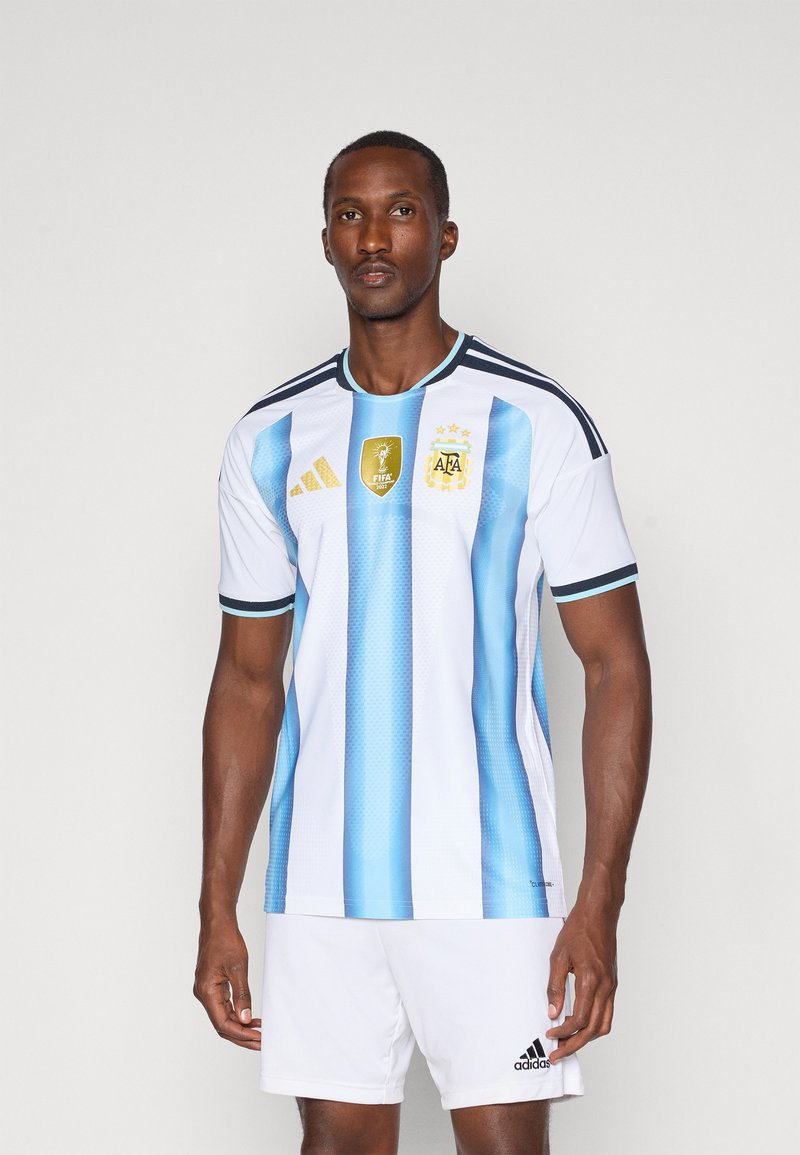 Camisola de futebol de manga curta branca com riscas verticais azuis, marca Adidas, logos dourados da FIFA e da AFA, e decote redondo.