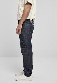 Mörka denimjeans med rak passform, som har sidofickor och synlig sömnad. Bakstycket har en logodetalj i beige.
