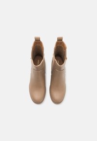 Bottines en cuir tan avec des orteils arrondis, des panneaux latéraux élastiques et des languettes de traction. Texture lisse avec des détails de couture minimal.