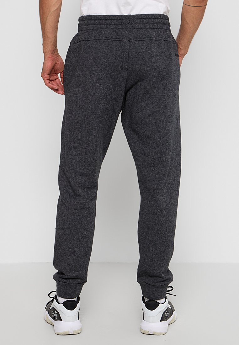 Pantalones de chándal grises hechos de una tela suave, con un corte relajado, cinturilla elástica y tobillos ajustados. Combinados con zapatillas negras y blancas.