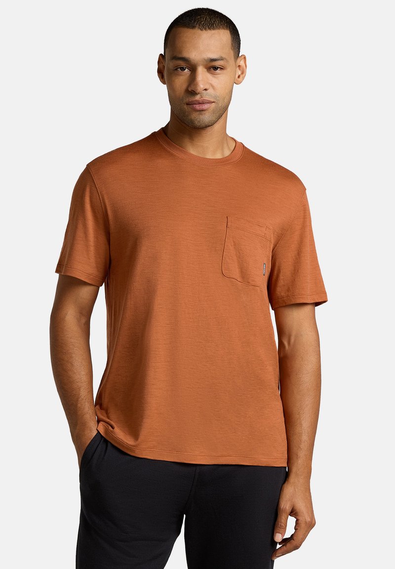 Rostfarbiges T-Shirt mit kurzen Ärmeln, Rundhalsausschnitt und Taschen auf der linken Brust. Weicher Stoff und lässige Passform.