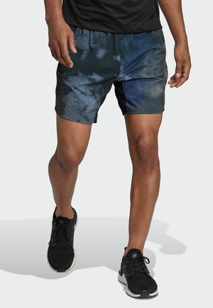 Pantaloni sportivi da uomo, con un design blu tonale e motivi testurizzati, vita elastica e tasche laterali, abbinati a sneaker nere.