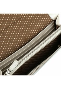 Witte portemonnee met een ritssluitingvak, bruine voering met witte stippen en meerdere kaartsleuven. Soepele textuur, rechthoekige vorm en metalen beslag.
