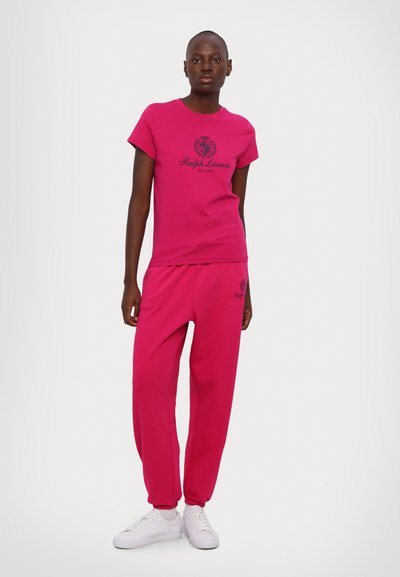 Conjunto de t-shirt de algodão rosa e calças de jogging com impressão de logótipo. O conjunto tem um corte descontraído, mangas curtas e punhos elásticos nas calças.