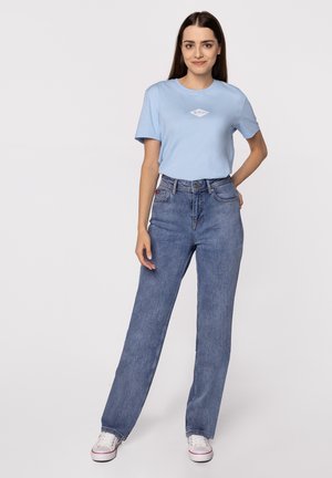Jasnoniebieska koszulka z krótkim rękawem z logo w kształcie diamentu, w zestawie z niebieskimi, wysokim stanem, prosto krojonymi dżinsami oraz białymi trampkami. Prosty design.