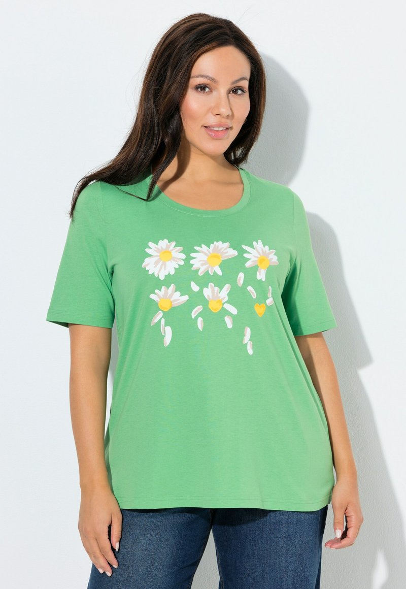 Grünes T-Shirt mit kurzen Ärmeln, versehen mit einem Blumenmuster aus weißen Gänseblümchen mit gelben Zentren, aus weichem, leichtem Stoff gefertigt.