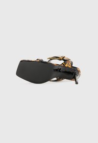 Sandalinha de salto alto preta com padrão floral em laranja e dourado, apresentando um design de tiras e um acabamento liso e brilhante na parte superior.