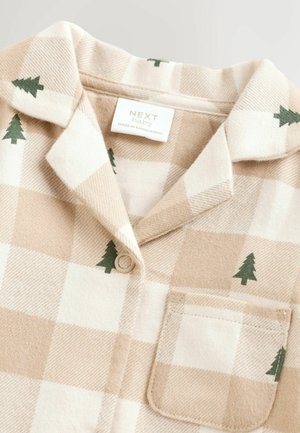 Béžová a biela kockovaná detská košeľa so vzorom malých zelených borovíc, s jedným gombíkom a vreckom na hrudi, označená "Next Baby."