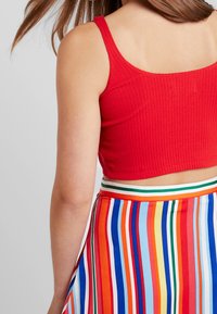 Top corto de rayas rojas con un falda de tiras multicolores que presenta rayas horizontales en azul, rojo, naranja, amarillo y verde.