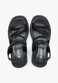 Czarne sandały z wieloma płaskimi paskami, kwadratowym noskiem i teksturowaną wkładką. Posiadają regulowany pasek wokół kostki z metalowym zapięciem.