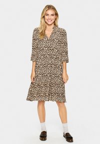 Rochie cu imprimeu de leopard, cu guler, mâneci până la trei sferturi, fustă învolută și croială lejeră. Prezintă culori maronii și crem.