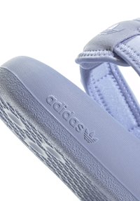 Fialové sandály Adidas s texturovanou gumovou podrážkou, nastavovacími popruhy a logem na boku. Hladké látkové akcenty.