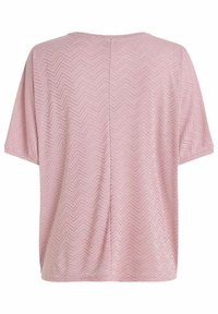 Pehmeä vaaleanpunainen lyhythihainen paita, jossa on hillitty kalanruotokuvio ja näkyvä keskisauma takana.