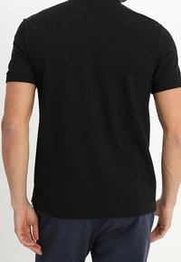 Polo shirt noir à manches courtes avec un col pointu, fabriqué en coton doux, avec un ourlet droit et des poignets côtelés.