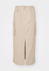 Jupe en coton beige avec une taille élastique, une fente à l'avant et deux poches cargo latérales. Coupe droite et texture douce.