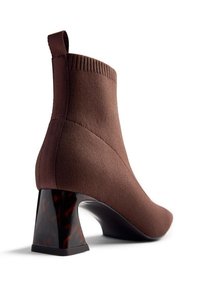 Botine tricotate maro, cu un guler cu nervuri și un toc bloc unic în nuanțe de broască țestoasă. Design elegant, aderent, cu o textură netedă.