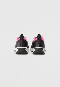 Black athletic shoes with pink accents, textured material, perforated sides, and white soles, showing a sporty design.