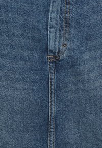 Džínové kalhoty v středně modré barvě, s klasickým střihem a rovnými nohavicemi, kontrastním oranžovým prošíváním a uzávěrem na jedinečný knoflík na pase.