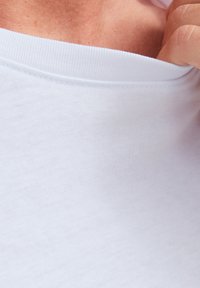 Effen wit T-shirt met een zachte, gladde textuur. Heeft een ronde halslijn en zichtbare stiksels langs de kraag. Dunne stof.