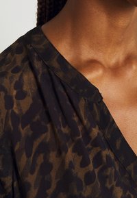 Černý a hnědý poloprůhledný top s jemným zvířecím potiskem, designem ve tvaru V a měkkou texturou, s nařasením na výstřihu.