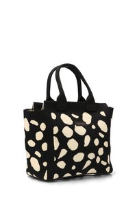 Bolso negro y crema con una superficie texturada, que presenta patrones de lunares irregulares, dos asas cortas y una forma rectangular.