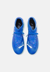 Scarpe da ginnastica blu con tomaia in maglia testurizzata, superficie decorata e logo bianco. Presentano lacci sottili e collo imbottito per il comfort.