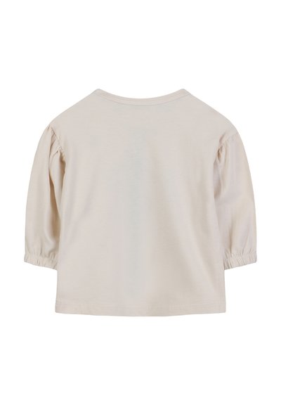 T-shirt en coton beige clair avec des manches courtes bouffantes, un col rond et une texture lisse. Design uni, sans motifs ni accents.