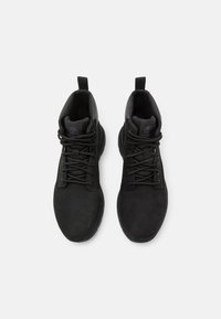 Baskets montantes noires en matière synthétique texturée, dotées d'un laçage et d'une boucle de traction sur le col.