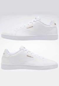 Baskets en cuir blanc avec logo Reebok doré, surface lisse, bout arrondi et semelle extérieure en caoutchouc plat. Lacets et col rembourré complètent le design.