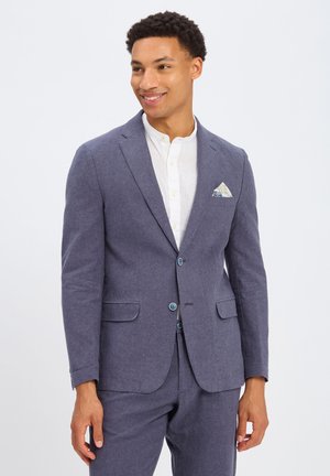 Marineblaue Leinenjacke mit zwei Knöpfen, Reverskragen und zwei vorderen Taschen. Ein gemustertes Einstecktuch setzt einen Akzent.