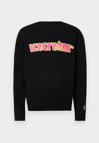 Svart hettegenser med et fargerikt "iskrem"-grafikk i gult og rosa. Har ribbestrikket rund hals og mansjetter, med et lite iskremikon på ermet.