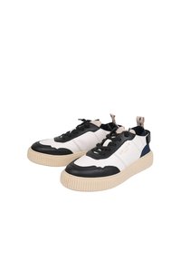 Baskets en cuir blanc et noir avec une surface texturée, bout rond et semelle en caoutchouc beige épaisse. Présente un système de laçage et des accents sur les côtés.