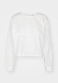 Blouse blanche courte en tissu texturé avec un motif paisley, col rond et manches longues avec poignets froncés.
