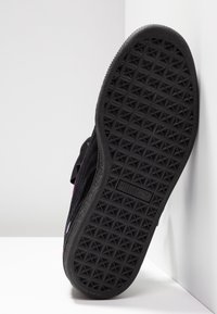 Svart sneaker-sula med ett texturerat mönster som har triangulära former, släta kanter och märkning med en logotyp. Skon har en låg profil.